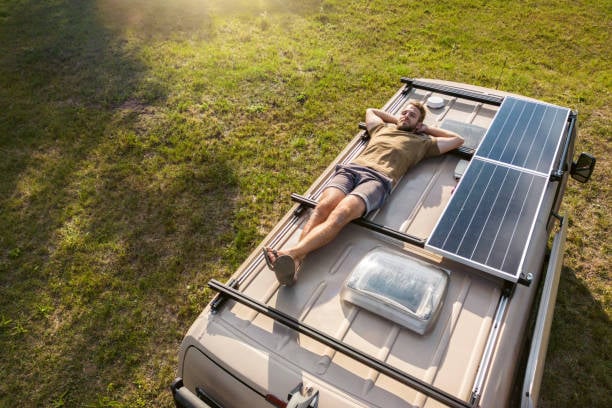 Guy laying on top of RV roof with solar panels